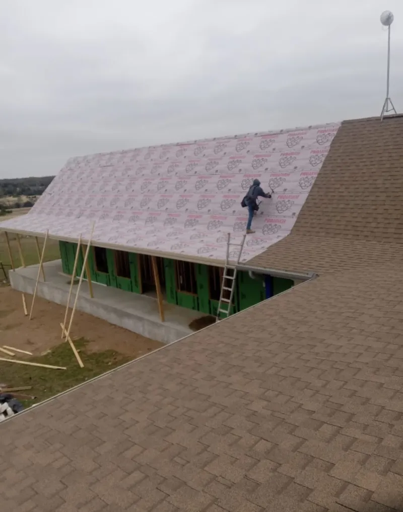 Worker preparing underlayment for a metal roof installation in Hartford City